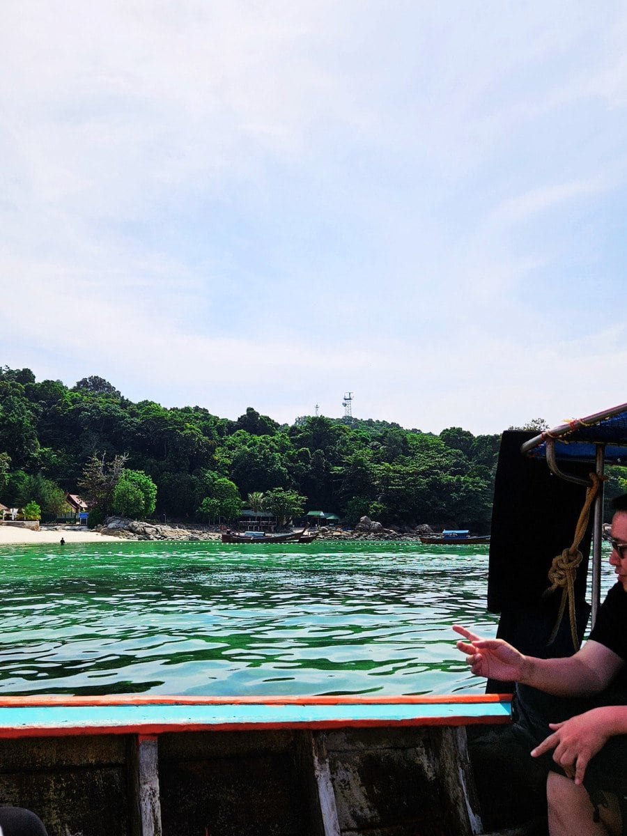 View from the boat sailing to the Pattaya Beach, Koh Lipe. Tourists sitting inside the boat, clear water, beach, boats in the distance