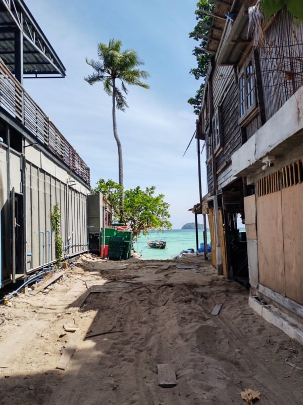 Path and entrance between the buildings to Sunrise Beach on Koh Lipe, palm tree in the horizon