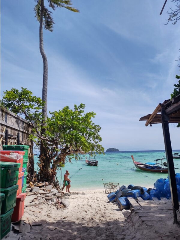 Path and entrance between the buildings to Sunrise Beach on Koh Lipe, palm tree in the horizon