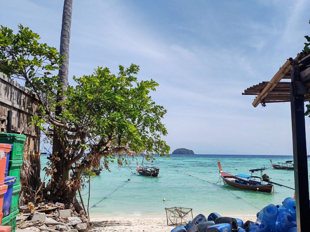 Path to the beach on Koh Lipe, blue water, boats, trees by the beach, islands in the distance