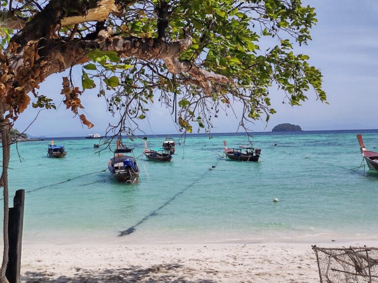 Blue clear water, boats by the beach and tree on Koh Lipe, Thailand