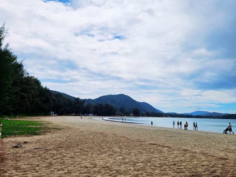 People walking on the beach, hills covered with jungle in a distance, Koh Lanta