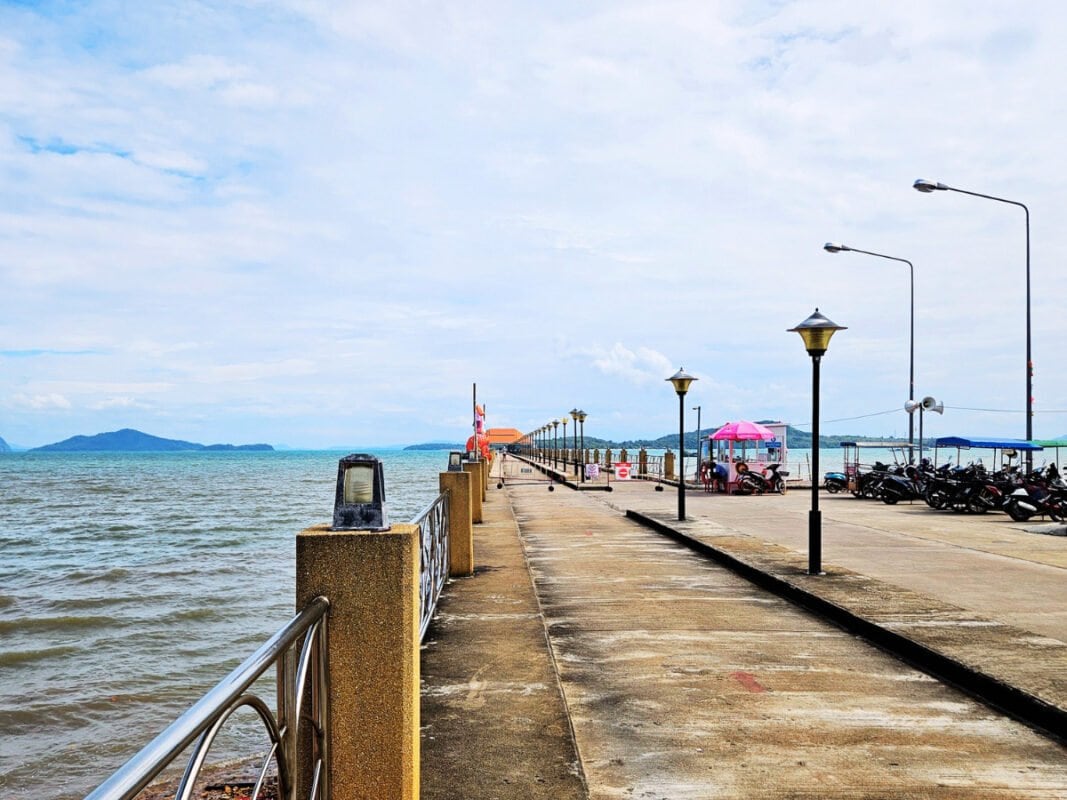 View of the pier by Koh Lanta Old Town, tuk-tuks parked on the right, sea and islands in the distance