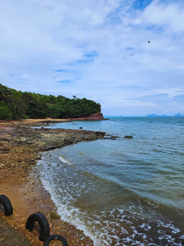 Waves crushing on the rocks, cliffs covered with jungle in the distance