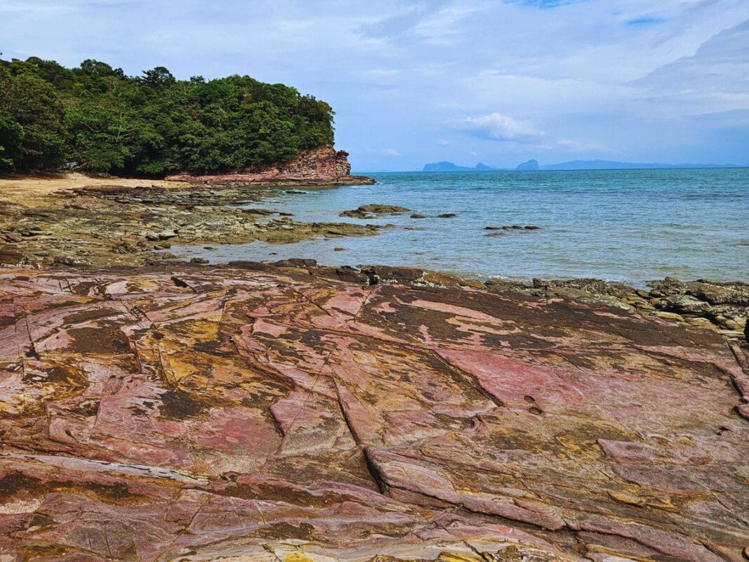 Red rocky shore on Pirate Bay; unique reddish rock formations along koh lanta coastline thailand