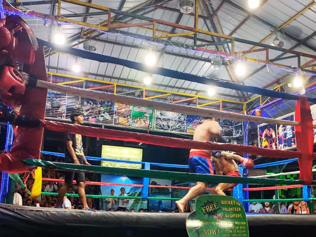 Boxing match at Koh Phi Phi, tourist fighting, Thai judge watching the fight, audience in the distance