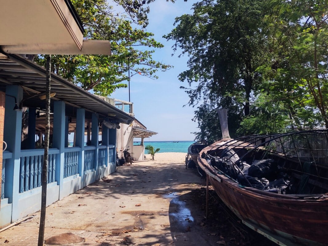 Koh Phi Phi path to long beach, buildings and boat, blue sea in the distance