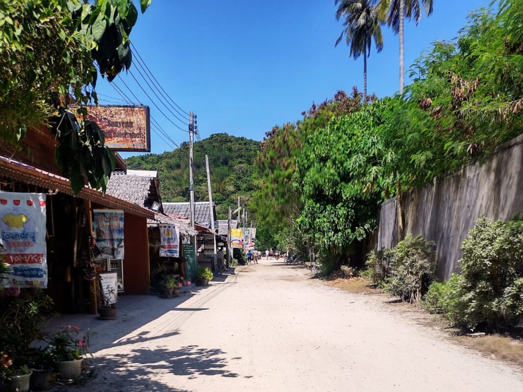 sandy street, small shops and restaurants on the right side, mountain in the distance