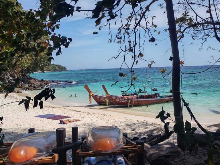 Koh Phi Phi kayaks and boats on sandy Wiking Beach, woman sunbathing on the beach