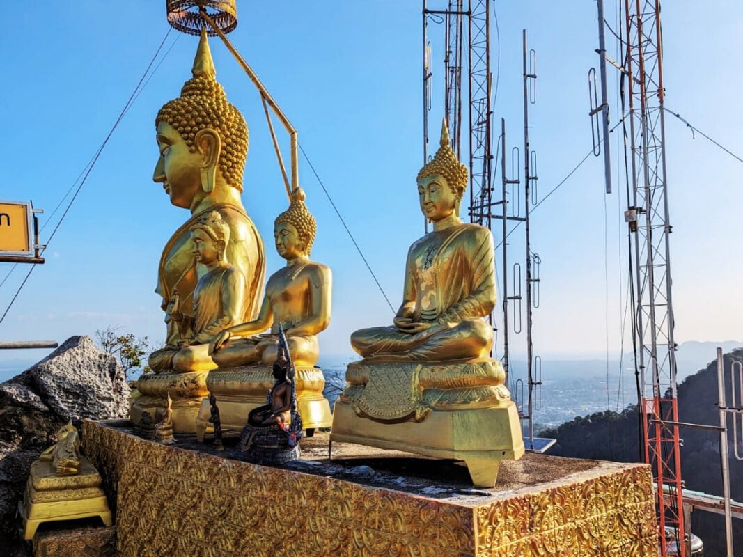 Three golden statues at the top of the Tiger Cave temple near Krabi town