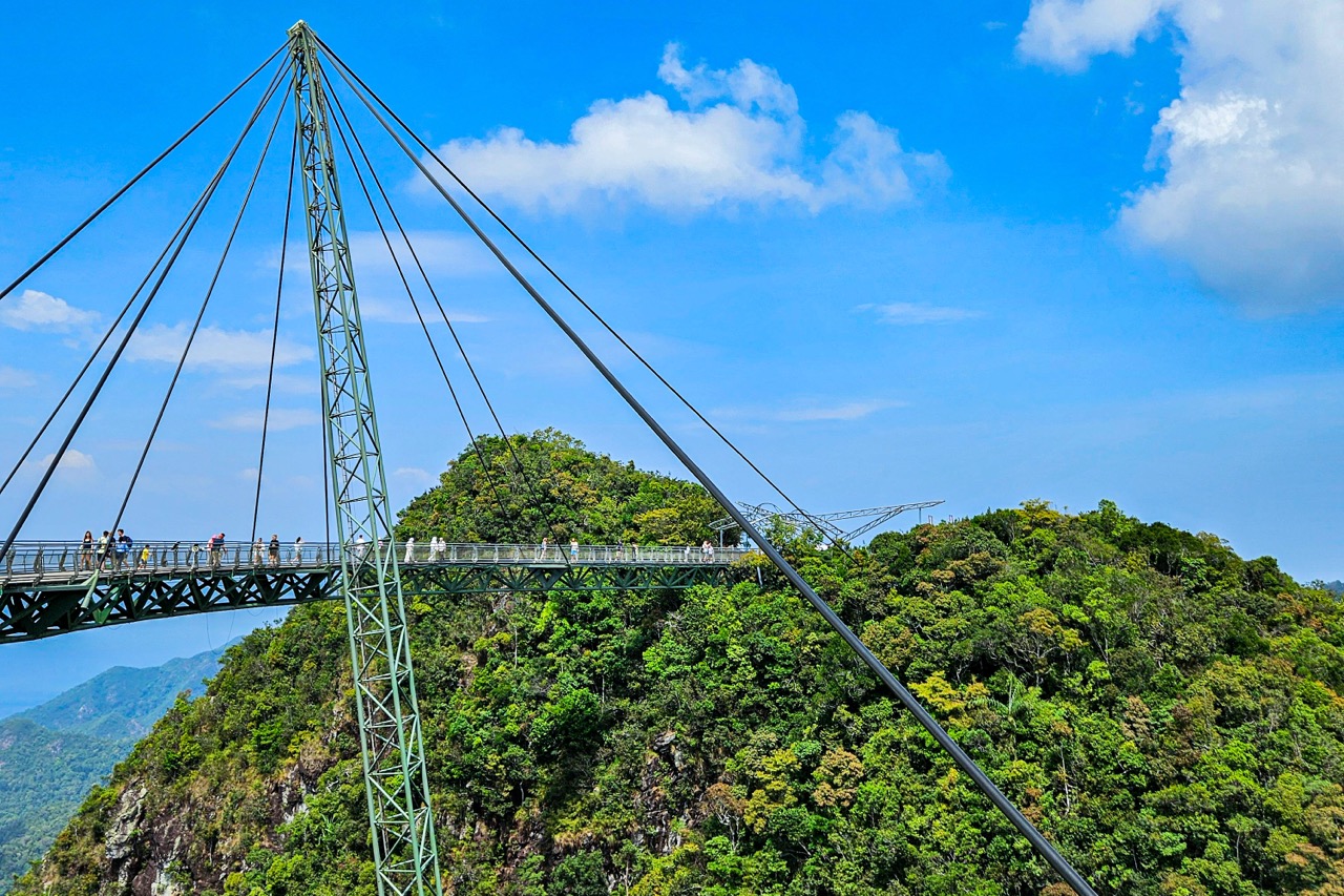 Suspension bridge walkway on the Skybridge on Langkawi, people walking on the bridge, views of the mountains in the background