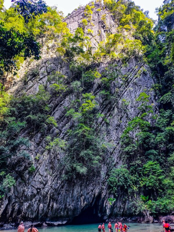 swimmers exiting emerald cave tunnel into lagoon koh mook thailand