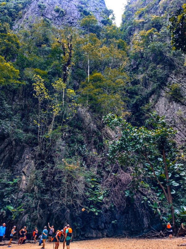 visitors standing on beach inside emerald lagoon morakot cave koh mook thailand