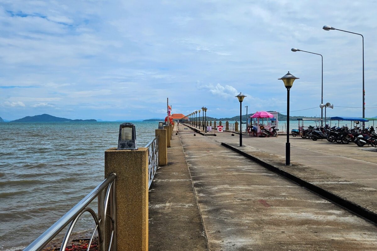 Koh Lanta Old Town pier stretching into the Andaman Sea with scooters parked near the harbor in southern Thailand
