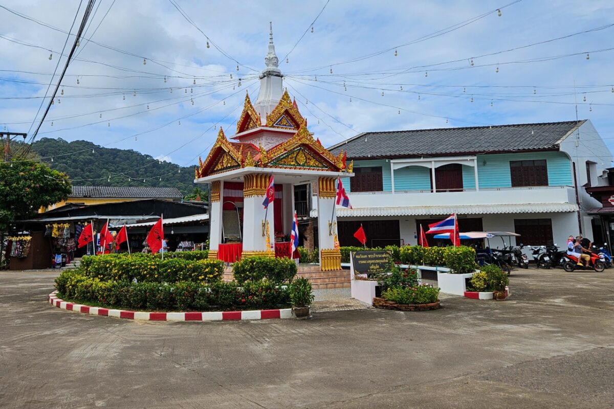 Small roundabout near the pier in Koh Lanta Old Town with Thai flags and local buildings in Southern Thailand