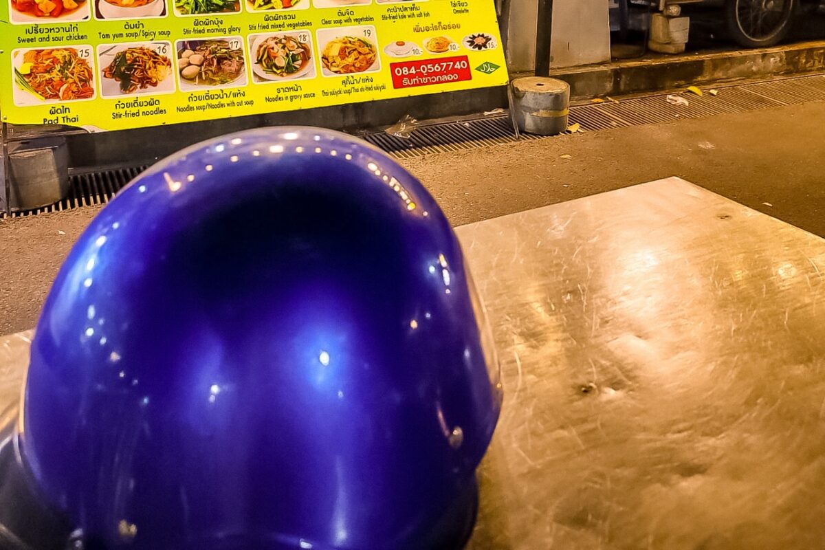 Local street food restaurant menu and scooter helmet on the table in Krabi Town, Thailand
