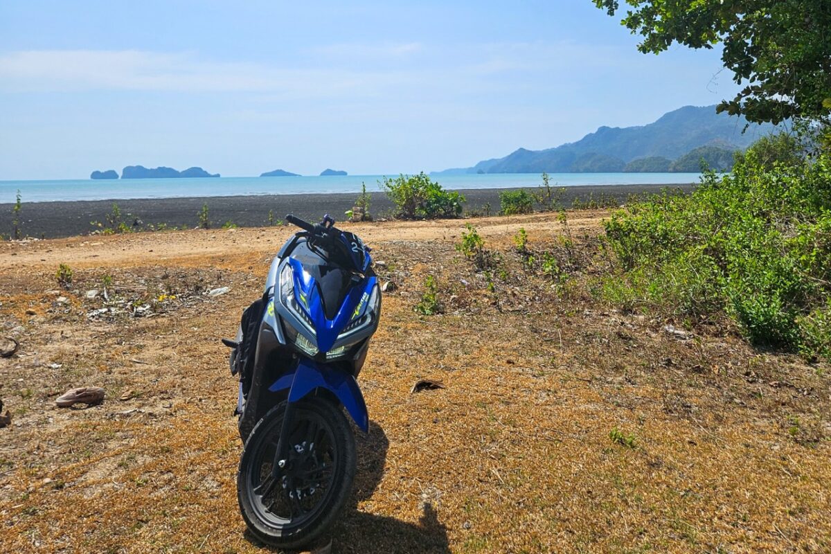 Scooter parked on coastal road with view of Pulau Tuba shoreline