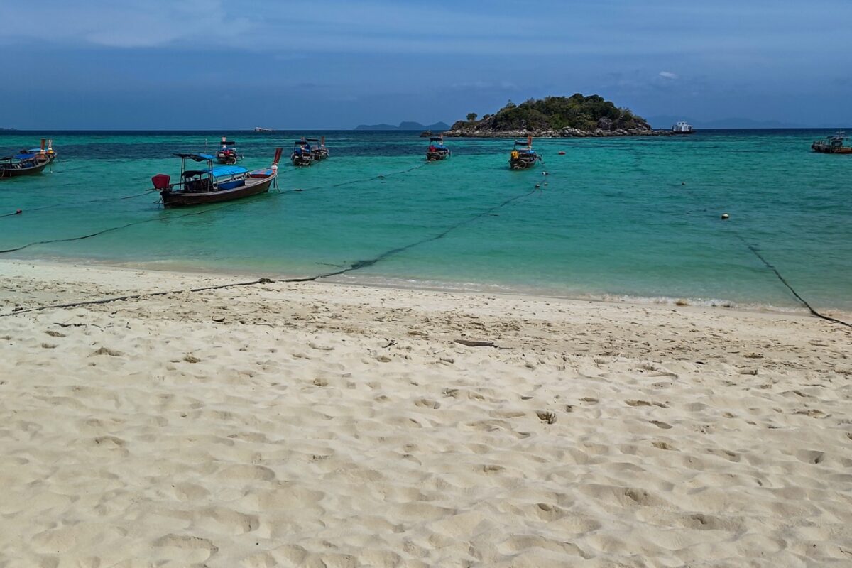 Longtail boats anchored at Sunrise Beach in Koh Lipe with turquoise water and white sand