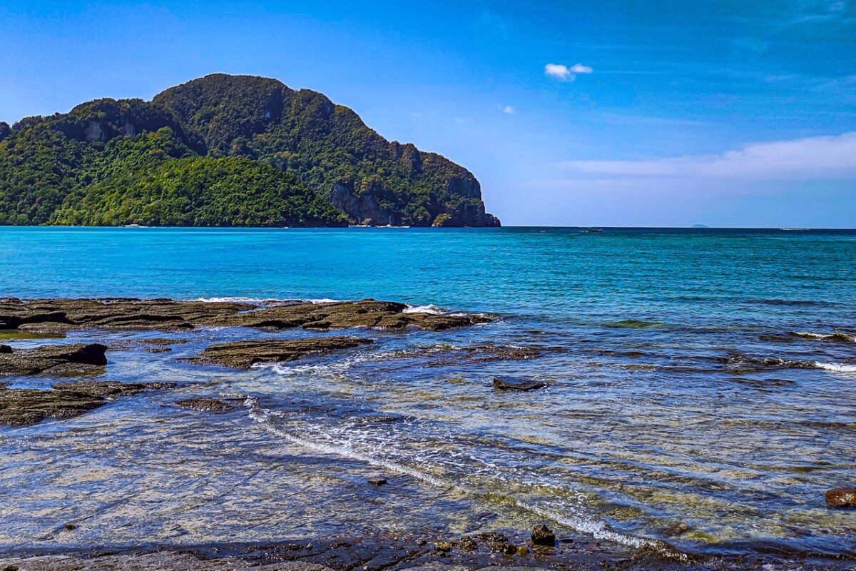 Rocky coastline Koh Phi Phi with turquoise water and jungle island in background